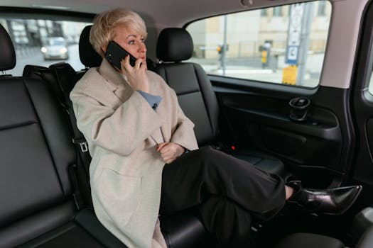 Woman in a car making a phone call, wearing a coat and resting comfortably.